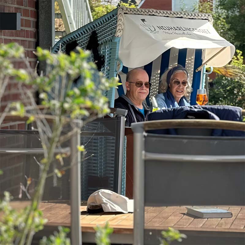Älteres Paar im Strandkorb hinter der Terrasse